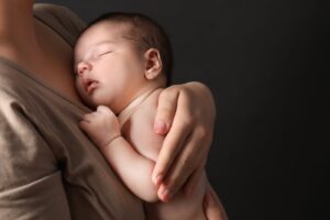 Mother holding sleeping baby, illustrating the connection between tongue ties and sleep problems